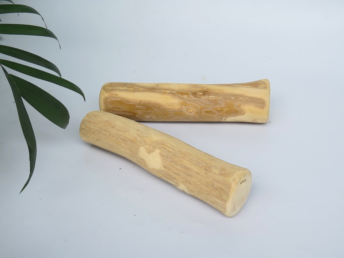 Two natural coffee wood dog chews shown on a linen backdrop