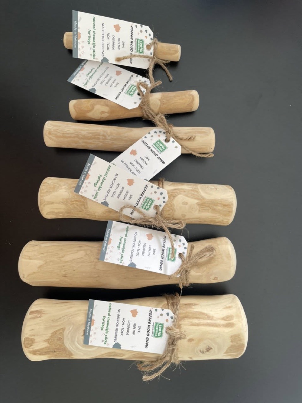 Coffee wood dog chews in six sizes, each with a kraft product tag and twine